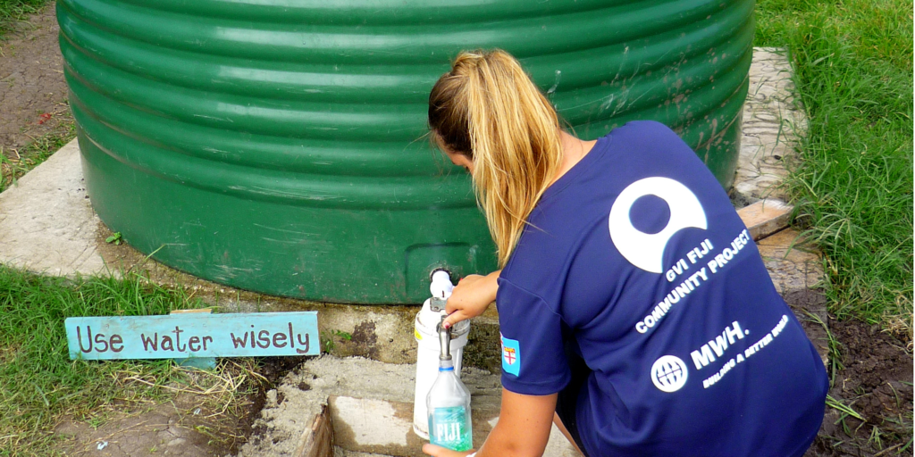 A GVI volunteer fills a water bottle from a water tank. 